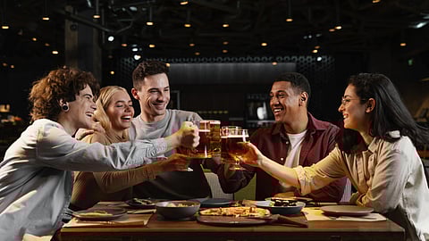 A group of friends is raising their drinks for a toast happily. 