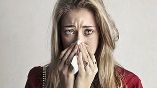 Image of a woman with light brown hair and a runny nose.