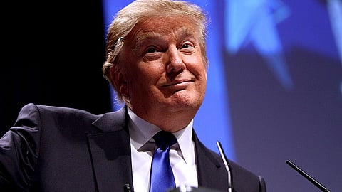 Image of President Donald Trump  wearing a black formal suit and giving a speech at an event.