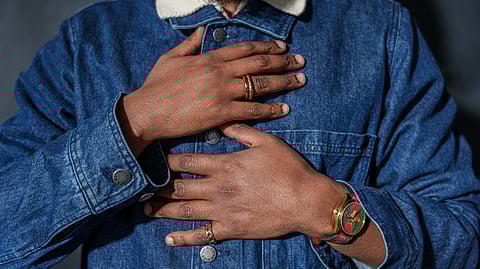 Image of a person wearing a denim jacket having hands around his heart.