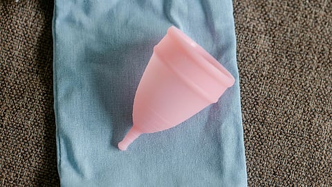 Image of a menstrual cup over a blue bag on a table.
