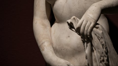 Image of an ancient statue of someone covering their genitals.