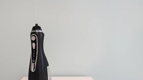 A black color oral irrigator kept on a white table. 