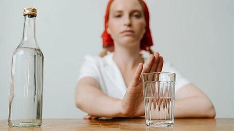 A woman sitting at a table with a glass of water and a bottle of water beside her.
