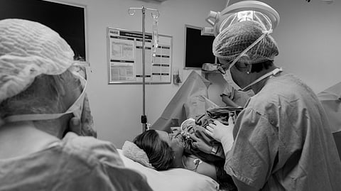 An image of a mother giving birth and doctors surrounding her.