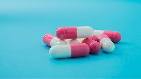 Image of antibiotic capsules in front of a blue background.