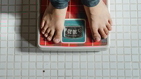 Image of a man weighing himself on a scale.