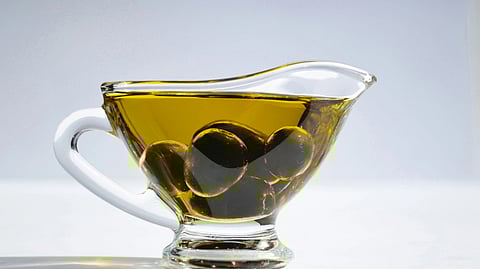 Image showing a cup of oil in front of a light blue background.