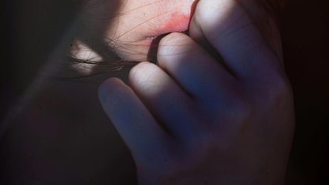 Close up image of a woman's face biting her teeth because of trauma caused due to dowry disputes.