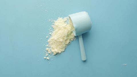 Image of a scoop of protein powder in front of a blue background.