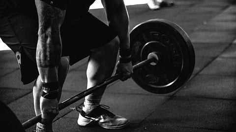 Black and white image of a person doing deadlifts in the gym.