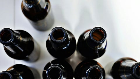 A collection of six empty beer bottles arranged together on a flat surface.