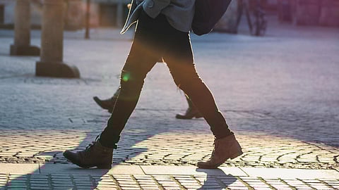 Image of a man walking on a street wearfing black jeans.