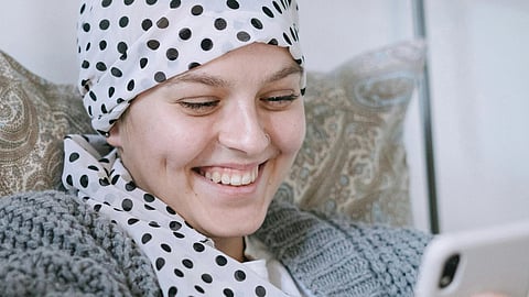 Image of a girl wearing a scarf and smiling at her phone.