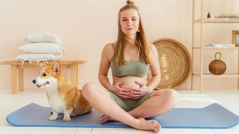 An image of a pregnant woman and a dog beside her.