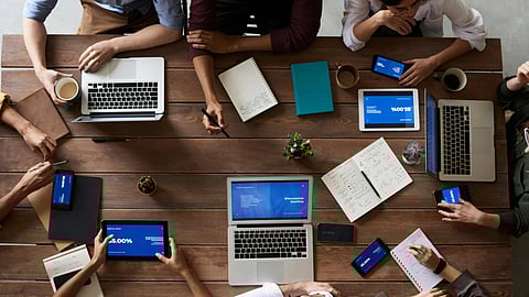 Image of employees working together in a single room sharing a single desk.