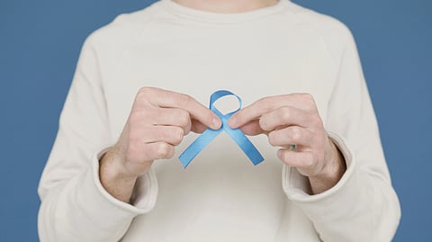 A man proudly holds a blue ribbon in his hands, symbolizing achievement or recognition.