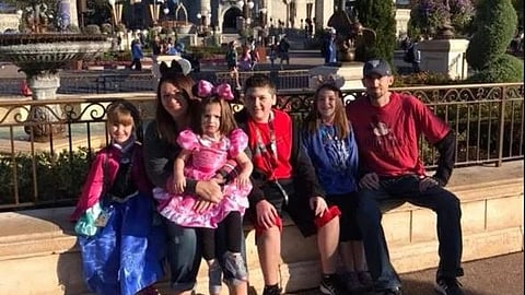 Family picture of Higginbotham family posing at a Disneyland. 