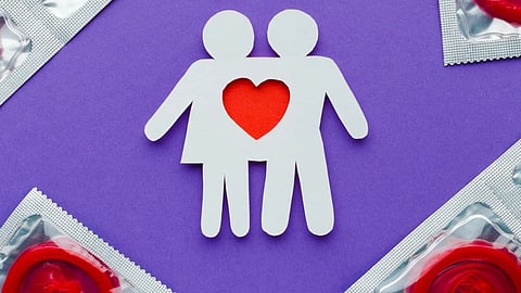 A paper craft of a couple standing embraced with a red heart in between.  
