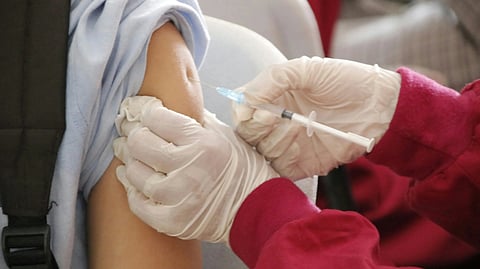 A patient receiving an injection from a doctor in a clinical setting.