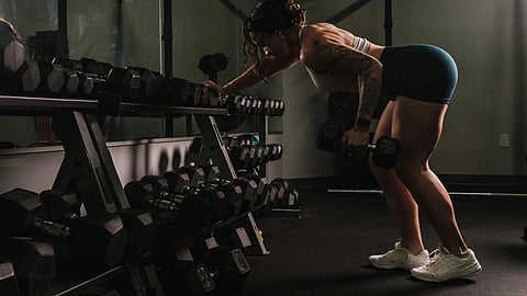 A woman performs a squat in a gym, focusing on her form and strength training.