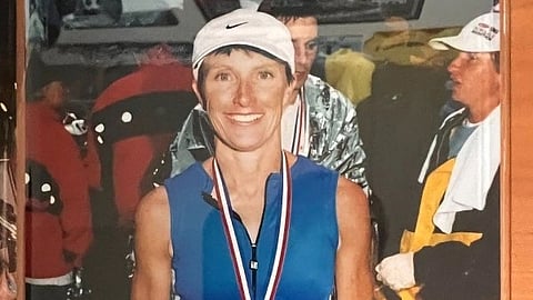 Image of Kathy Graef wearing a blue zipped tank top and a white cap along with a medal.