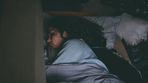 Image of a woman sleeping in her bed with blankets and pillows.