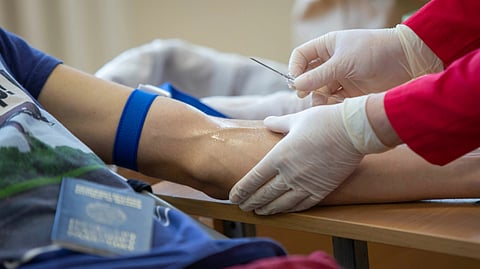 A doctor draws blood from a patient seated in a medical office, focusing on the procedure with care.