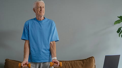 An image of an older man exercising with small dumbells.