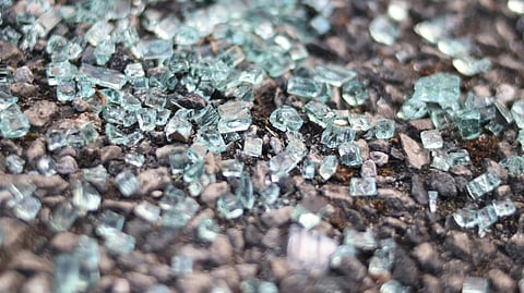Shattered glass scattered on the ground, reflecting light in various directions.