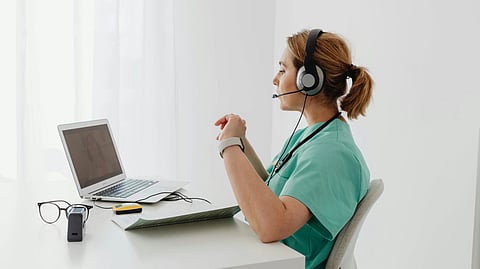 An image of a healthcare staff with laptop and headphones.