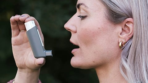 An image of woman using an asthma inhaler.