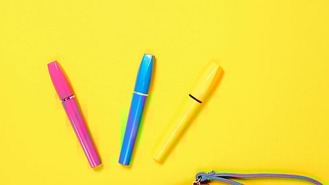 Image of beauty pens in front of a yellow background.