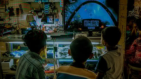 Three children are engaged in playing video games together inside a store, surrounded by various gaming displays.