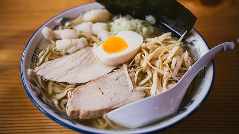 A bowl of ramen topped with slices of meat and soft-boiled eggs, garnished with green onions.