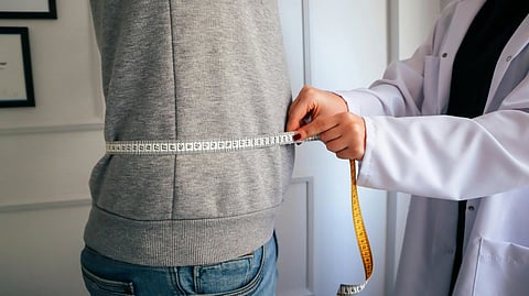 Image of a doctor measuring waist of a patient.