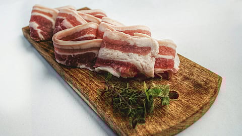Image of crispy bacon strips arranged on a rustic wooden cutting board.