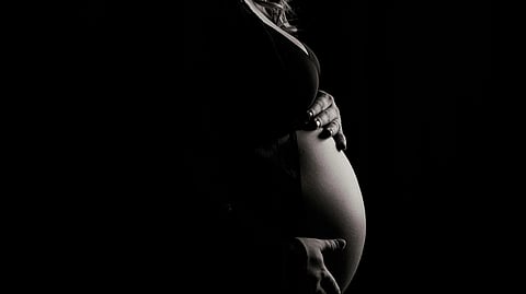 Black and white image of a woman holding her pregnant belly.