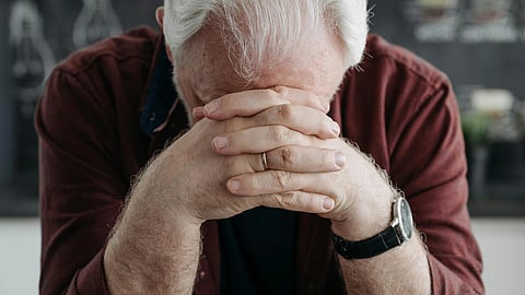 Image of an old man wearing a brown shirt in very sad mood.