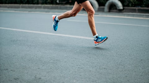 A runner in motion on a street, showcasing a pair of sporty shoes.