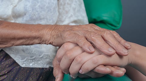 A close-up image of an elderly hand gently resting on a younger hand.