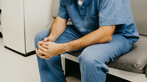 An image of a male healthcare staff looking distressed.