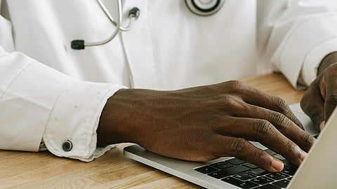 A doctor typing on a laptop, focused on their work in a clinical setting.