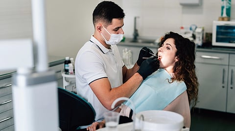 A man and woman sitting together in a dental office, discussing dental care with a dental professional nearby.