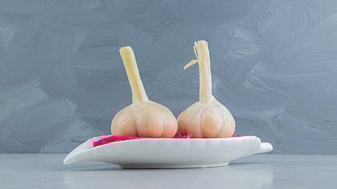 An image of two garlics on a white plate.