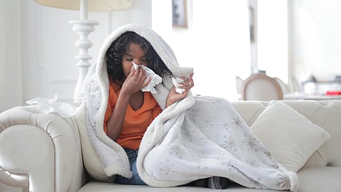 An image of a woman sits on a couch, wrapped in a cozy blanket, creating a warm and inviting atmosphere.
