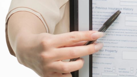 Close up image of a woman pointing on a document using a pen.