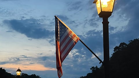 A street light adorned with an American flag, symbolizing patriotism in an urban setting.