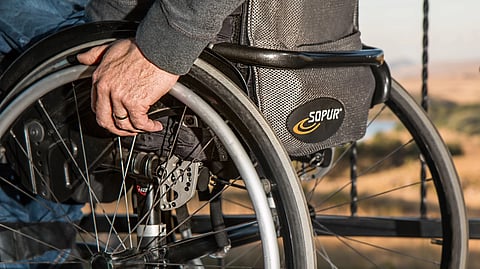 Image of a person’s hand gripping the wheel of a wheelchair.