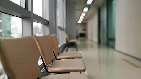 Empty chairs line a hospital hallway, creating a quiet and sterile atmosphere.